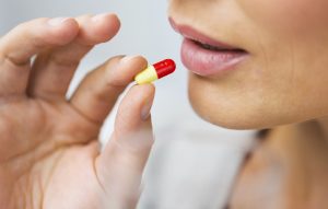 close up of woman taking medicine in pill