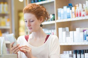Lady reading cosmetics label - Learn more about cosmetic expiration dates