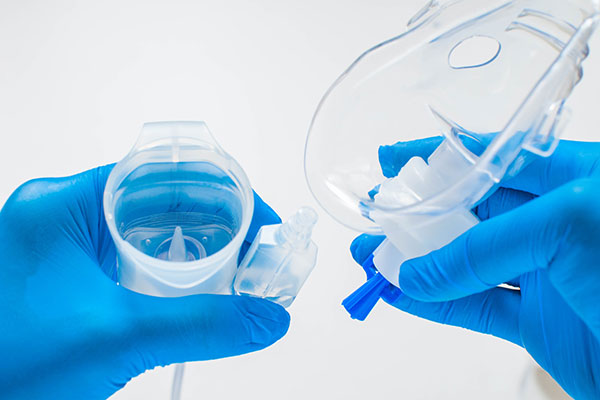 photo of a person wearing medical gloves holding a nebulizer