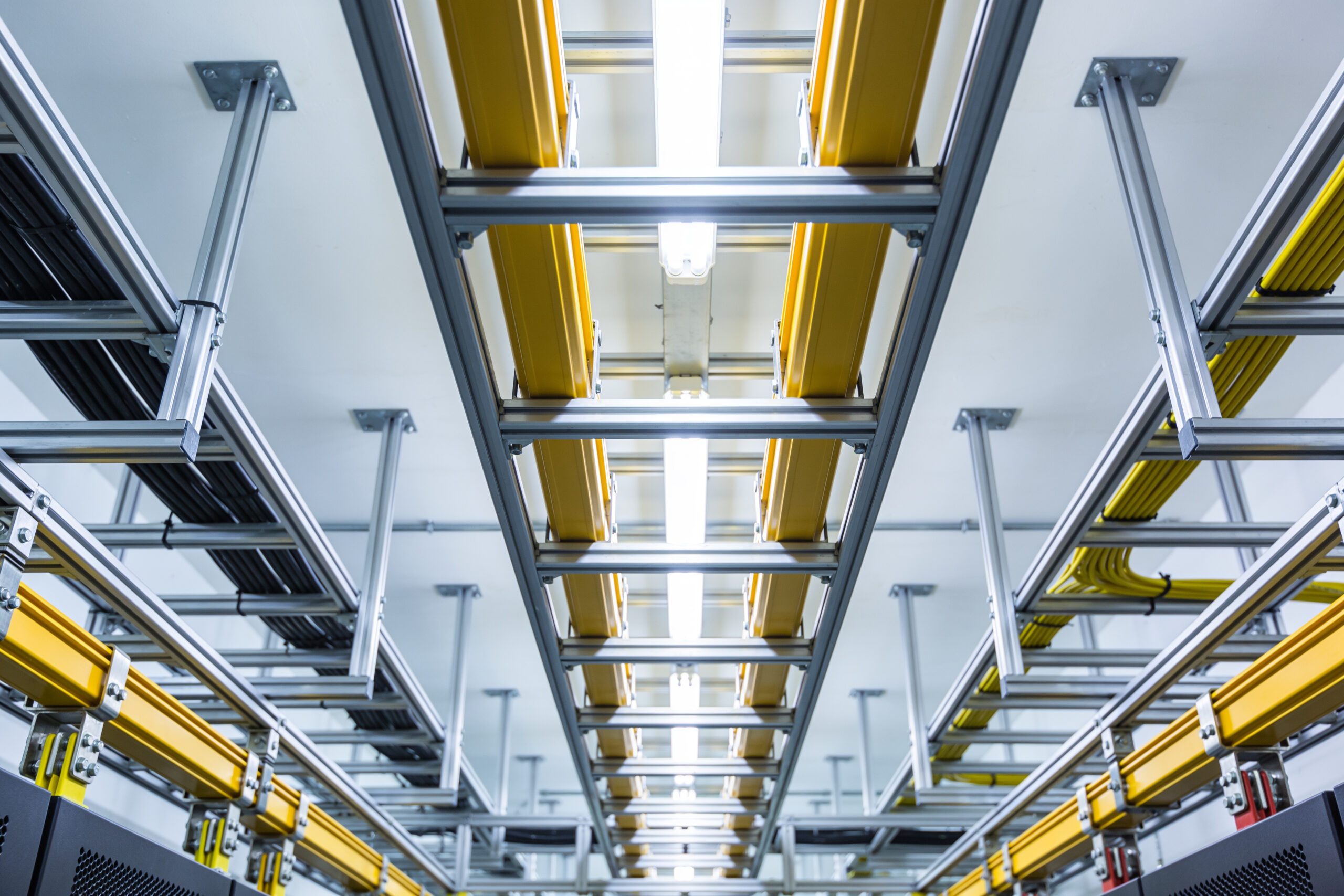 Overhead cable trays and yellow raceways converging in data center