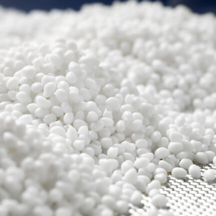 Closeup of a white plastic polymer granule in a laboratory on a blue background.