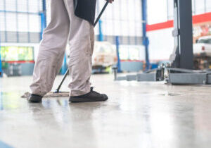 mechanic in auto repair center Cleaning using a mop Squeeze water from the epoxy floor. in the car repair service center