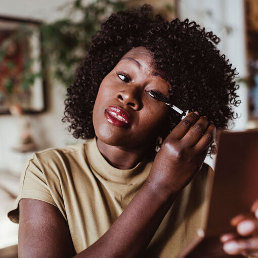 Mature Afro woman applying mascara at home