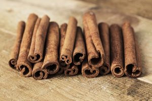 Stack of cinnamon wrapped with a rope over a wooden surface