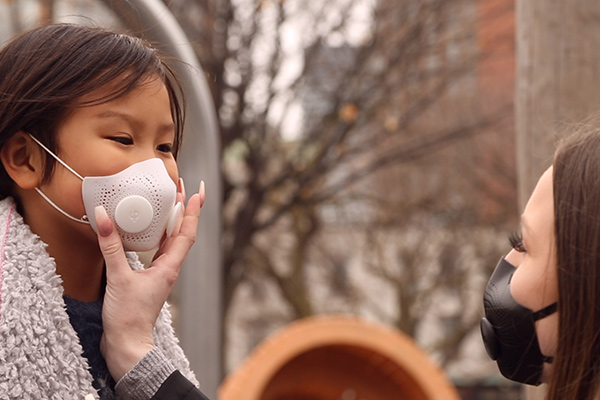 Photo of a mother helping child with a face mask - Learn more about LuxMea’s bespoke face mask 