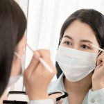 woman wearing mask applying eyeshadow - Learn more about cosmetic trends
