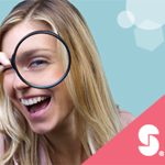 Smiling woman looking through magnifying glass