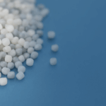 HDPE resin pellets on blue surface, symbolizing recyclable and versatile thermoplastic used in packaging and piping