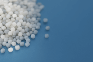 HDPE resin pellets on blue surface, symbolizing recyclable and versatile thermoplastic used in packaging and piping