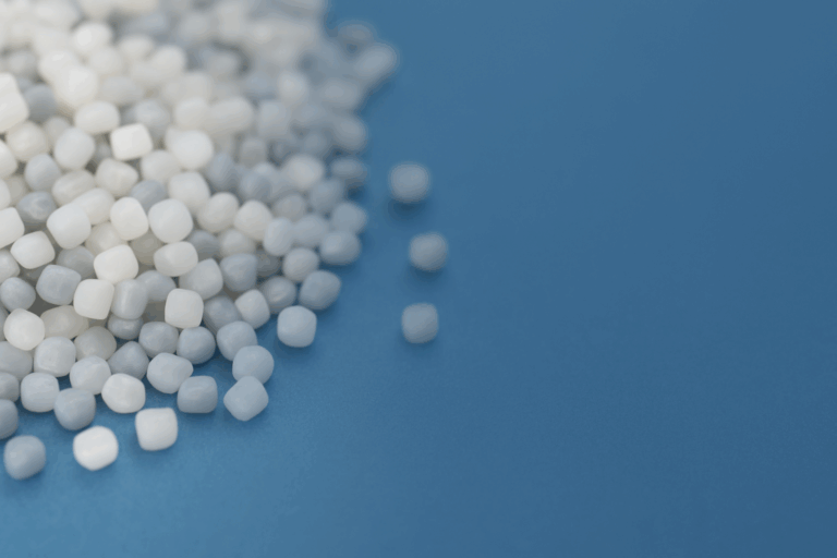 HDPE resin pellets on blue surface, symbolizing recyclable and versatile thermoplastic used in packaging and piping