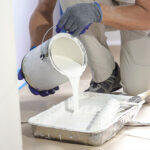 Worker pouring white paint