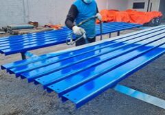 a painter is painting a steel surface blue for a steel building