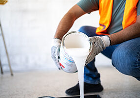Painter/construction worker pouring paint indoors