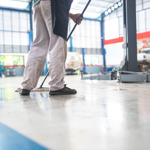 mechanic in auto repair center Cleaning using a mop Squeeze water from the epoxy floor. in the car repair service center