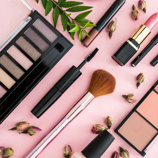 Make up natural cosmetics flat lay. Lipstick and nail polish, eye shadows and blush, brushes, pencils and rose buds against pink color background.