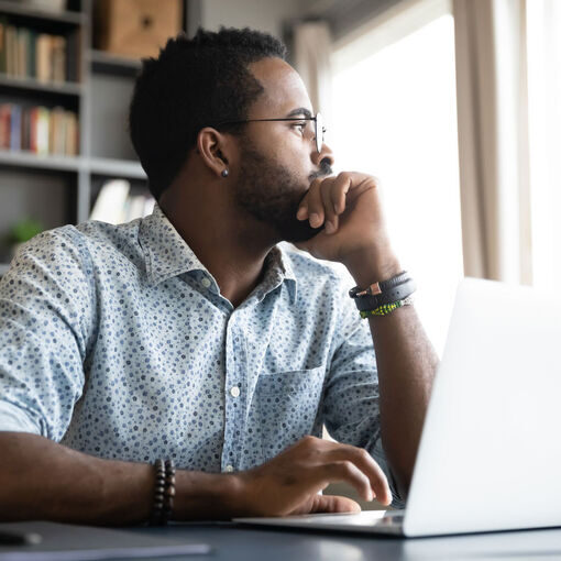 Thoughtful serious african professional business man sit with laptop thinking of difficult project challenge looking for problem solution searching creative ideas lost in thoughts at home office desk